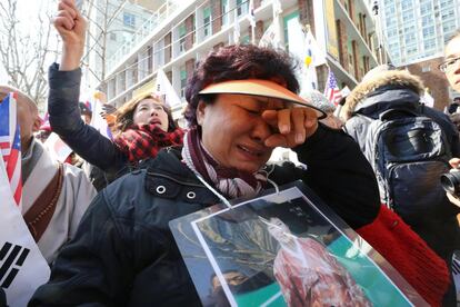 Tras la lectura del veredicto se han producido violentos choques entre la policía y los partidarios de la ya expresidenta frente a la sede del tribunal y en la cercana avenida Sejong de Seúl. En la imagen, una mujer llora tras conocerse el fallo del Tribunal Constitucional.