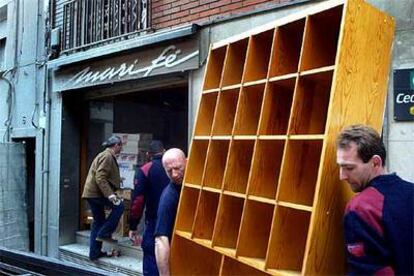 Dos empleados de una empresa de mudanzas retirando mobiliario de la tienda de ropa de Mari Fe Fernández, ayer en el barrio del Carmel.