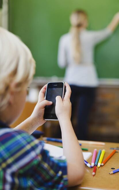 Un niño usa el móvil durante una clase.