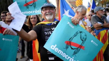 Un grupo de catalanes a favor de la independencia muestran carteles por la democracia y papeletas del refer&eacute;ndum del 1-O.