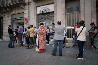 Varios ciudadanos hacen cola a la espera de ser atendidos en una oficina de servicios sociales en Barcelona.