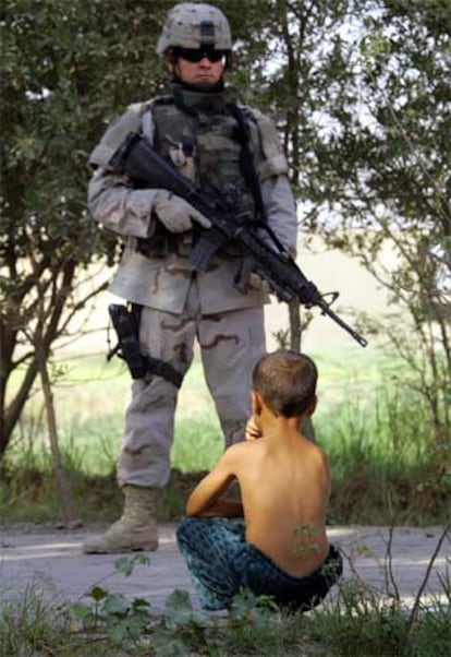 Un soldado de EE UU vigila a un niño cuyo padre fue detenido por esconder armas en su domicilio, ayer en Bagdad.