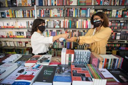 Dos mujeres limpian sus manos en una caseta en la Feria del Libro de Madrid.