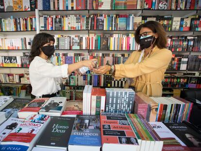 Dos mujeres limpian sus manos en una caseta en la Feria del Libro de Madrid.