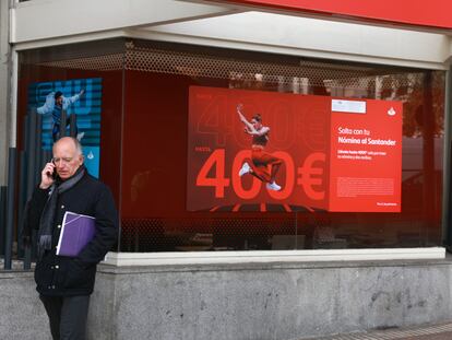 Un hombre habla por teléfono delante de una sucursal del Banco Santander, en Madrid.