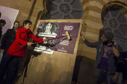 Podemos candidate Teresa Rodríguez puts up a campaign poster.