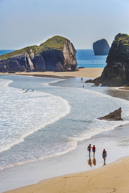 La senda costera que atraviesa Llanes muestra entre Poo y Celorio su apabullante hegemonía. Un mundo de prados sobre precipicios catalogados como paisaje protegido; una tersura de arena húmeda en sus playas que demanda ajustarse a la bajamar. Con el oleaje a distancia prudencial, bajamos por la escalera del Portiello. Así comienza el magnífico paseo por las cuevitas de los cantiles, acercándonos a los castros nimbados de bruma, por donde imparte clases de surf Planeta Palombina (planetapalombina.com). Algunos extienden la toalla en el tómbolo que se forma en bajamar apoyado al castro (islote) de San Martín, maravilla del gusto naturista cuyo baño resulta peligrosísimo. Al este, la isla y playa de Almenada. Junto al esqueleto de la ermita de San Martín, en plena ruta compostelana, se abre una panorámica muy fotogénica. <p><b>Acceso:</b> en Poo enlazamos con la senda costera sentido Celorio durante 15 minutos. Una vez visitado Portiello, restan 700 metros hasta la ermita de San Martín.</p>