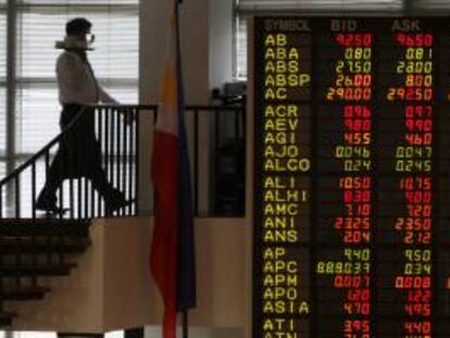 Un camarero camina junto a un panel con información bursátil en el parqué filipino en Makati, al sur de Manila, Filipinas. EFE/Archivo