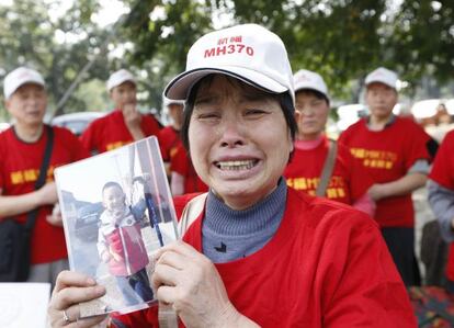 Una mujer muestra la foto de su nieto, cuyo padre desapareció en el vuelo MH370.