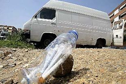 Una botella con jeringuillas, ayer en el barrio de Porta, con una furgoneta abandonada que utilizan los toxicómanos al fondo.