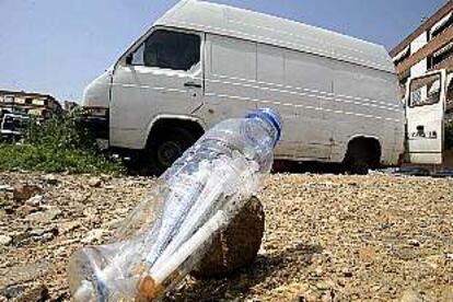 Una botella con jeringuillas, ayer en el barrio de Porta, con una furgoneta abandonada que utilizan los toxicómanos al fondo.