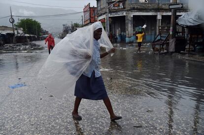 Una mujer intenta protegerse del viento y de la lluvia con un trozo de plástico, en Puerto Príncipe.