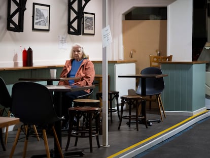 Una mujer sentada sola en una cafetería en Cardiff (Gales, Reino Unido).