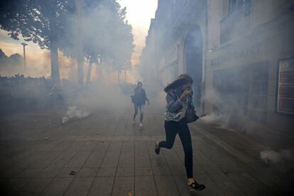 Manifestantes intentan ponerse a salvo del gas lacrimógeno lanzado durante una protesta en contra de la reforma laboral, en París.