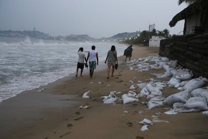 Personas caminan por la playa en Acapulco horas antes de que 'Otis' tocara tierra, el 24 de octubre.