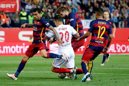 El jugador del Sevilla Vitolo (2-i) cae entre (i-d) Dani Alves, Gerard Piqué y Rafinha, del FC Barcelona.