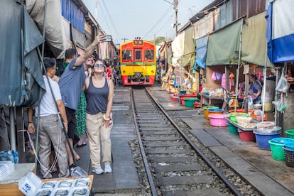 Multitud de empresas ofrecen hoy productos turísticos en los que incluyen excursiones que giran alrededor de “hacerse la foto” para poderla compartir en redes. En la imagen, dos turistas en el Mae Klong Railway Market. 