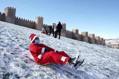 Un hombre disfrazado de Papá Noel se tira en trineo por el lienzo norte de la muralla de Ávila, el viernes.