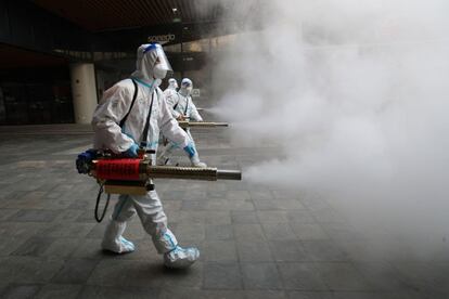 Personal sanitario rocía con desinfectante en el exterior de un centro comercial en Xian (China). La ciudad lleva ya más de tres semanas de confinamiento por un brote detectado en diciembre, aunque los medios locales informan de una relajación de las restricciones a medida que el número de contagios ha caído este lunes y martes a menos de 20.