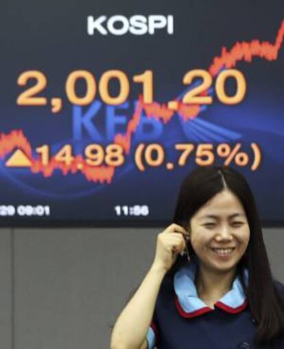 Una trabajadora del Korea Exchange Bank sonríe frente a un monitor que muestra los datos del índice Kospi, en Seúl, Corea del Sur.