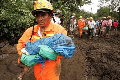 Un bombero sostiene en brazos el cadáver de un niño en la localidad guatemalteca de Panabaj.