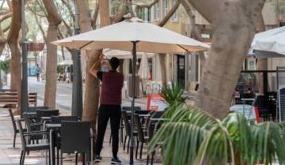 Un camarero coloca una sombrilla en la terraza de un bar en la calle Betenchourt Alfonso de Santa Cruz de Tenerife.