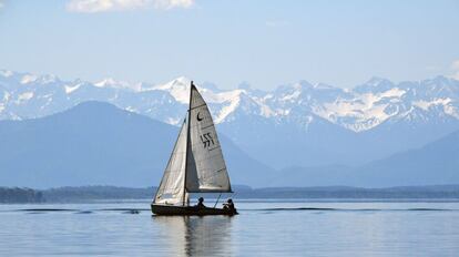 Un barco navega en el lago Starnberger See como en el fondo se puede ver un panorama de los Alpes cerca de Starnberg, en el sur de Alemania, donde las temperaturas alcanzaron los 28 grados centígrados el 3 de junio de 2019.