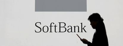 Una mujer usa su tel&eacute;fono m&oacute;vil frente a un logotipo de Softbank.