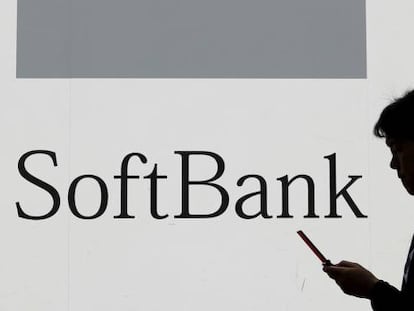 Una mujer usa su tel&eacute;fono m&oacute;vil frente a un logotipo de Softbank.