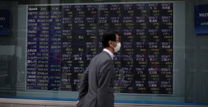 Un hombre con mascarilla, ante un panel de cotizaciones en Tokio.