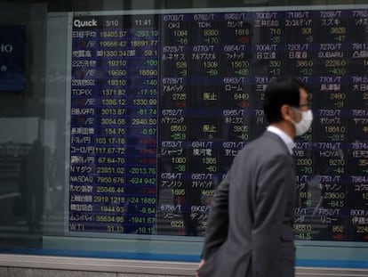 Un hombre con mascarilla, ante un panel de cotizaciones en Tokio.