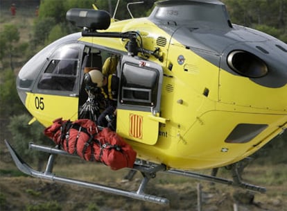 Un helicóptero de los bomberos sube uno de los cadáveres.