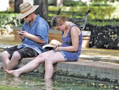 Dos turistas se refrescan en el Prado de San Sebastián de Sevilla.