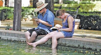 Dos turistas se refrescan en el Prado de San Sebastián de Sevilla.