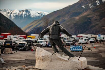 Estatua del esquiador a la entrada del parquing público de Baqueira, donde, al fondo, se sitúan las autocaravanas.