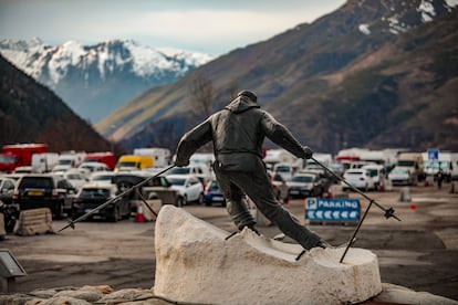 Estatua del esquiador a la entrada del parquing público de Baqueira, donde, al fondo, se sitúan las autocaravanas.