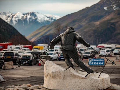 Estatua del esquiador a la entrada del parquing público de Baqueira, donde, al fondo, se sitúan las autocaravanas.