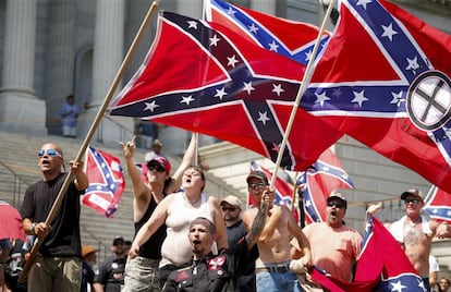 Extremistas del Ku Klux Klan exhiben banderas confederadas este sábado ante el Capitolio de Carolina del Sur en protesta por la retirada de la enseña por sus connotaciones racistas, mientras profieren insultos a miembros del grupo radical Panteras Negras, congregados allí también para celebrar la decisión.