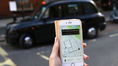 Una usuaria de Uber frente a un taxi de Londres.