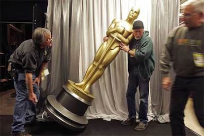 Dos operarios colocan el viernes una de las figuras que reproducen las estatuillas de los Oscar en el Kodak Theatre de Los Ángeles.