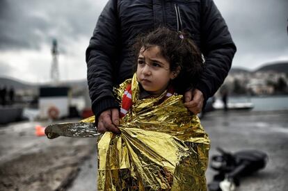 Un padre refugiado junto con su hija envuelta en una manta térmica llegan al puerto de Mitilene, en la islas de Lesbos (Grecia), depués de cruzar el mar Egeo desde Turquía.