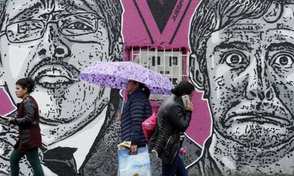 Varias personas caminan delante de un mural del asesinado humorista Jaime Garzón, en Bogotá (Colombia).