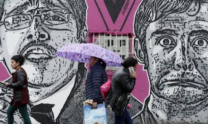 Varias personas caminan delante de un mural del asesinado humorista Jaime Garzón, en Bogotá (Colombia).