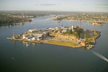 Vista aérea del islote, tras el que la bahía de Sídney se transforma en Parramata River. La isla Cockatoo sigue manteniendo su fisonomía industrial, con sus dársenas, sus grúas, sus naves, pero ahora ha sido transformada en un atractivo enclave cultural y de ocio.