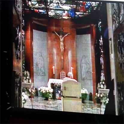El Papa, de espaldas, sigue las imágenes del vía crucis.