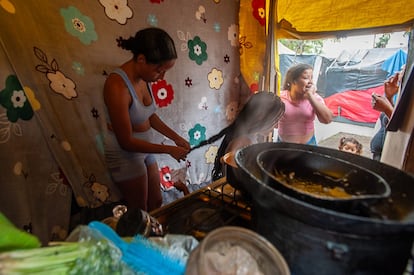 Gabriela Arévalo trenza el cabello de una amiga en la cocina de su vivienda improvisada.
