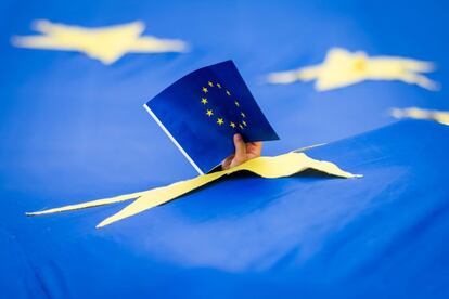 Un niño sostiene una bandera de la Unión Europea a través de un agujero de una gran bandera, en Bucarest (Rumania).