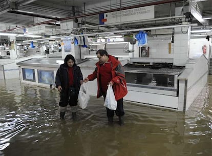 Dos comerciantes del Mercado de La Ribera se disponen a abandonar el recinto, cuyo desalojo fue ordenado por la Mesa de Crisis del Ayuntamiento de Bilbao.