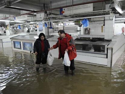 Dos comerciantes del Mercado de La Ribera se disponen a abandonar el recinto, cuyo desalojo fue ordenado por la Mesa de Crisis del Ayuntamiento de Bilbao.