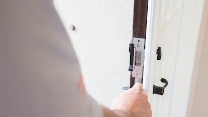 La mano de una persona poniendo el pestillo en la puerta.